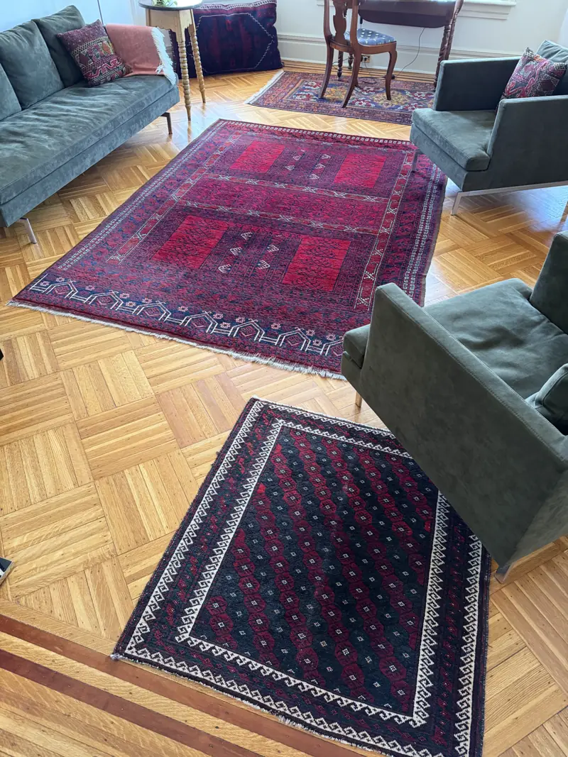 Three patterned rugs with green armchairs on a parquet floor