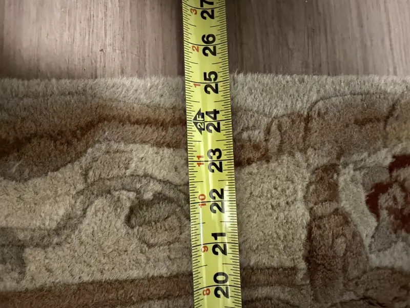 A tape measure across the field of a cream rug