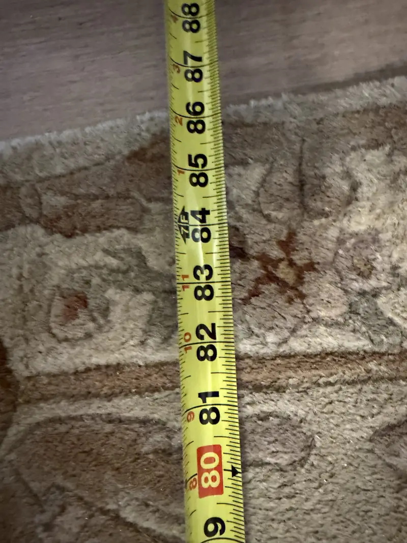 A tape measure laid on the pile of a cream rug
