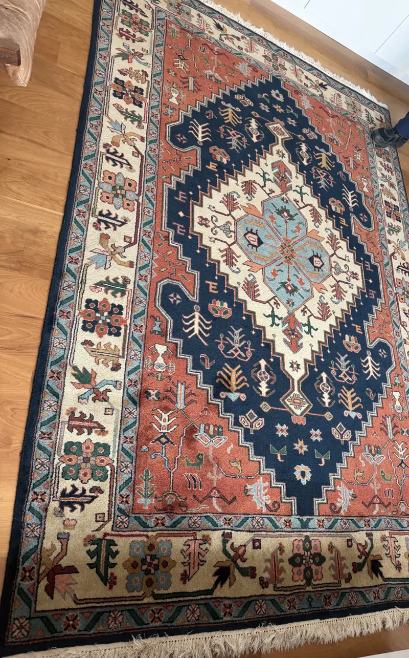 A rug with a large blue and ivory medallion on a wood floor