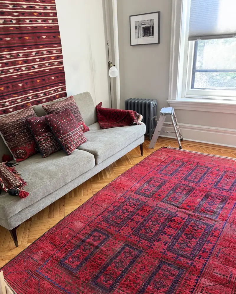 A red rug in a bright living room with a grey sofa